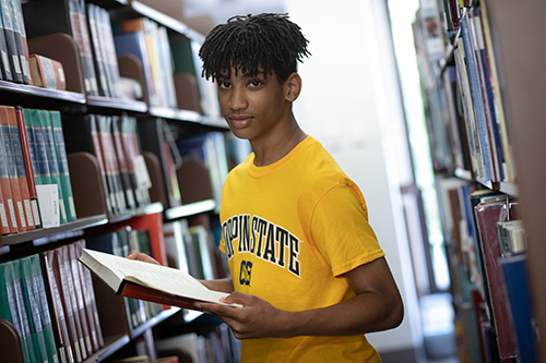 A young student in the library holds a book