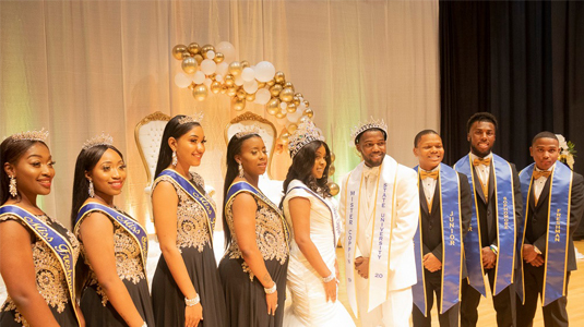 Posed picture of 9 Coppin students dressed formally while wearing their royal court regalia