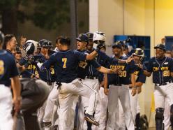 Multiple members of the Coppin State University men's baseball team wearing baseball uniforms while celebrating and hugging 
