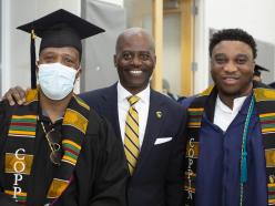 Dr. Jenkins taking picture with two graduates at commencement
