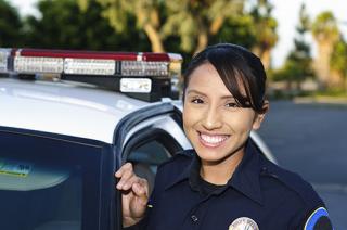 A female police officer in uniform stands by a police car