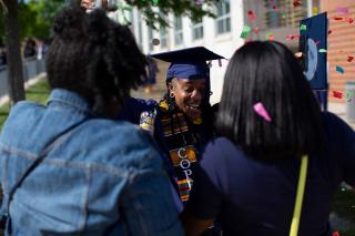 A graduate at commencement celebrates with family
