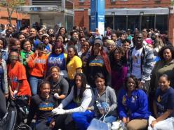 A large group of Black male and female students posing in front of a Coppin State University building
