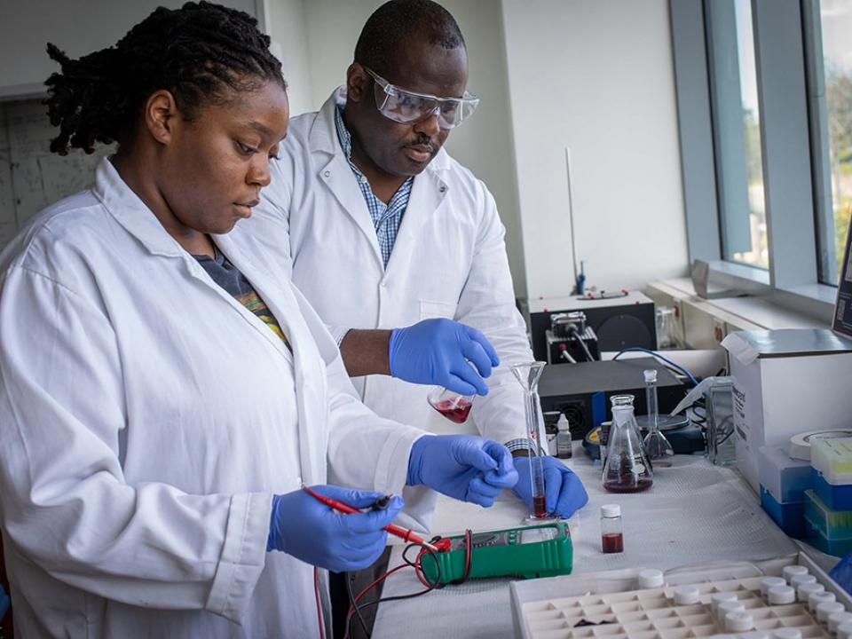 A female science student wearing a lab coat working in the lab
