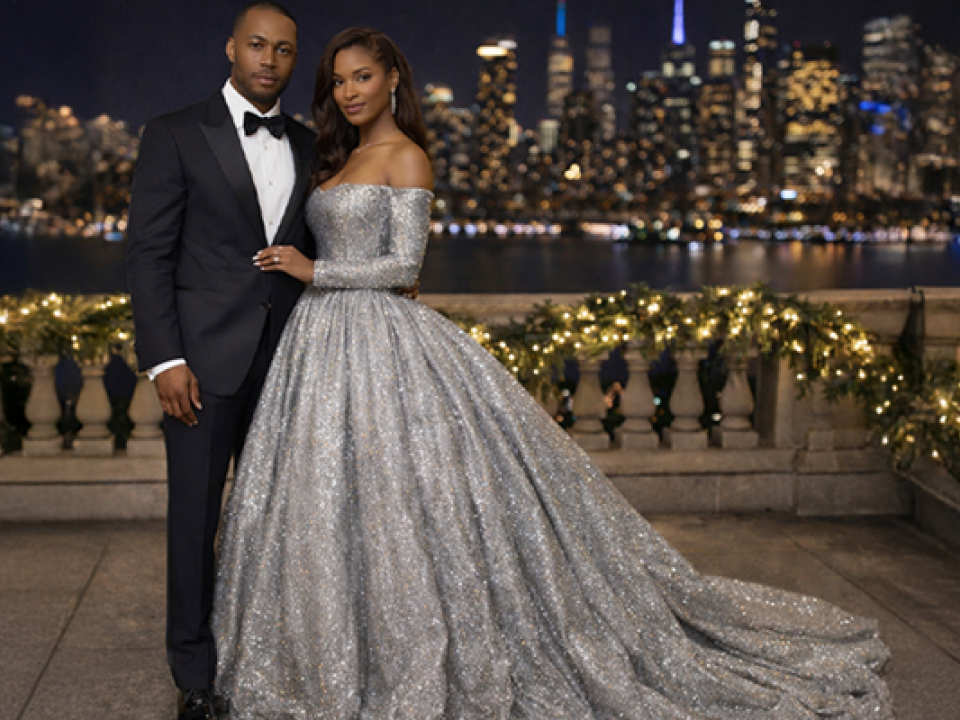 Stock image of couple on balcony with city skyline in background.