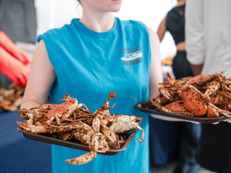 Server holding two plates of steamed crabs at Coppin Crab Feast.