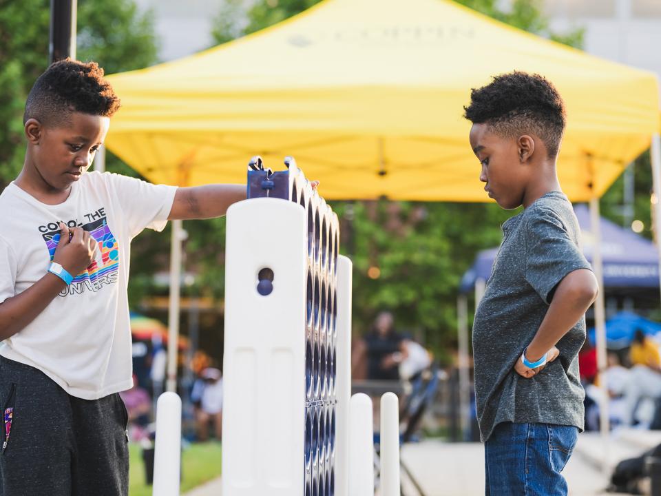 Two youngsters playing giant Connect Four at Coppin Summer Concert.