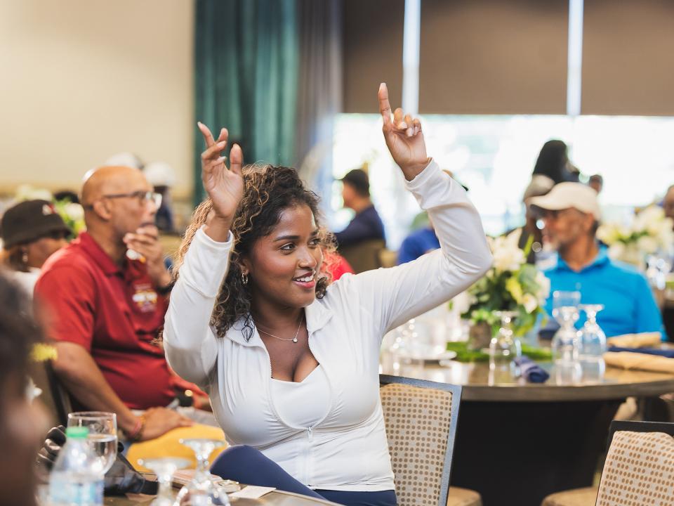 Woman with hands up at Coppin Golf award ceremony.