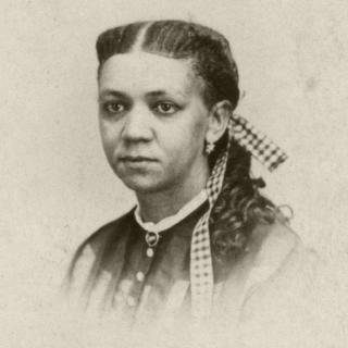 Black and white headshot photo of Fanny Jackson Copin with hair braided with gigham ribbon while also wearing a button up blouse