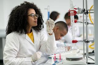 Female student in class at the lab looking at a test tube