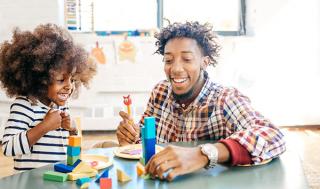 A teacher engages an excited child with toy blocks