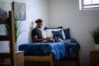 Student siting on bed in the dorm