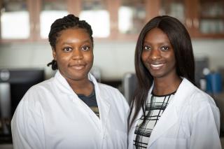 Two female students wearing lab coats in the science lab