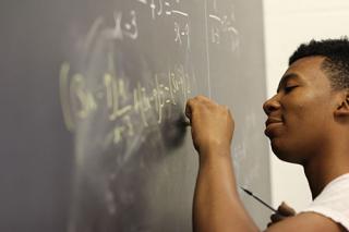 student doing math on chalkboard