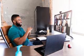 A male seated at his desk participates in a video conference