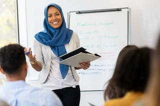 A teacher conducts a class in front of a whiteboard