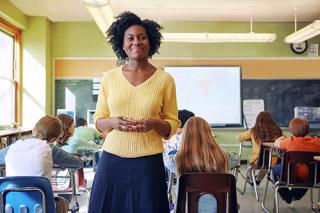 A teacher in a classroom of young students working at their desks