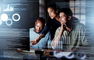 Shot of a group of programmers working together on a computer code at night