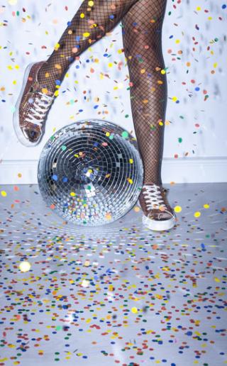 Dancing with sneakers, disco ball, and confetti in the air.