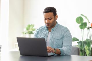 Portrait of focused male with laptop sitting at the desk