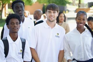 four students in white polo shirts smiling