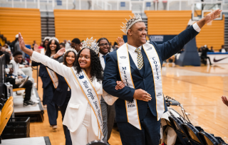 Mister and Mister Coppin with the royal court waving to the crowd in the PEC during homecoming.